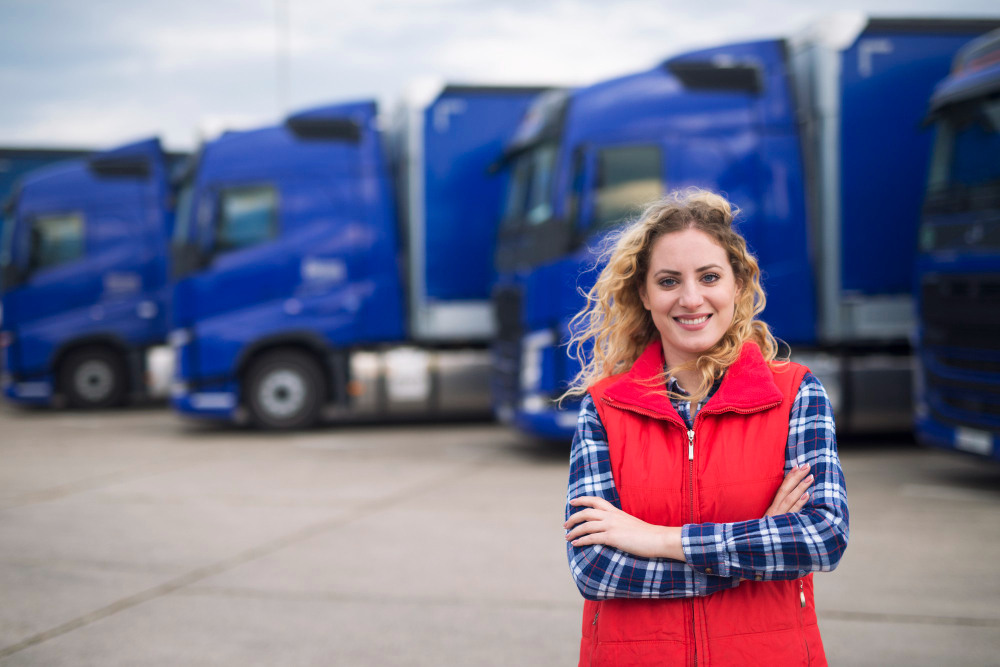 Logistics professional standing in front of freight trucks at a transport facility